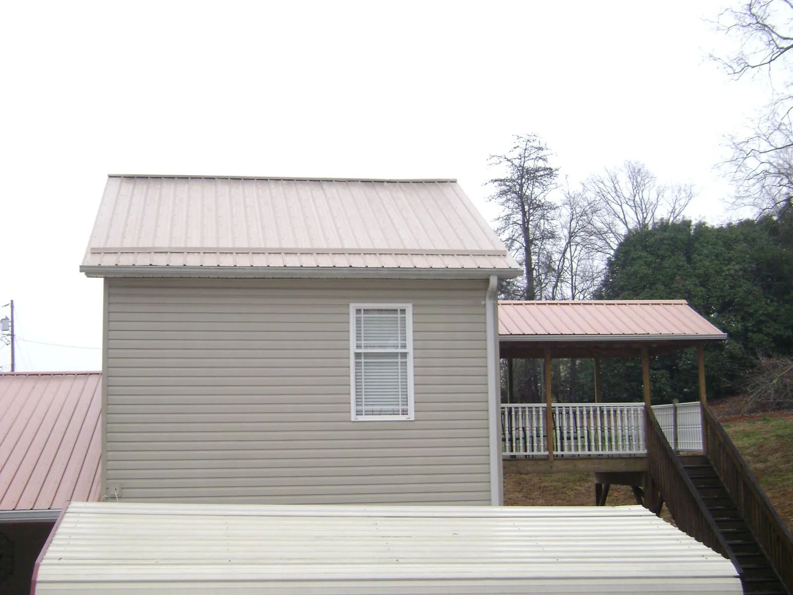 Tan metal roofs on a two story addition and attached porch, from a Roof Replacement job in La Fayette